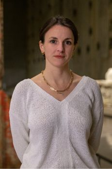 Portrait of a woman standing in a dimly lit room, associated with teaching 9/11 through diverse narratives.