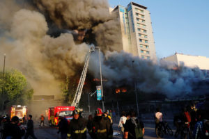 Chile protests: Firemen work to put out flames as a shopping mall burns during an anti-government protest in Santiago, Chile October 28, 2019. REUTERS/Henry Romero